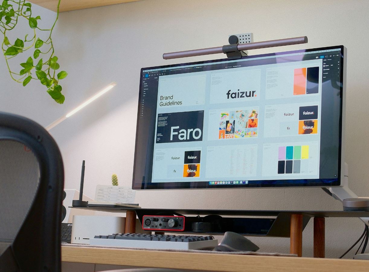 A computer monitor sits on a desk in a room. The monitor displays a design document from an interface design tool.