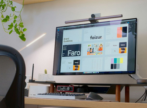 A computer monitor sits on a desk in a room. The monitor displays a design document from an interface design tool.